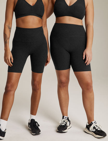 Two models wear marled black Spacedye High Waisted 7" Biker Shorts with matching bras, showing a snug mid-thigh fit.