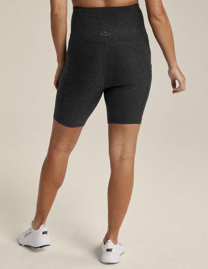 Woman wearing Darkest Night Spacedye Pockets Forever Maternity Biker Short™ in a rear view with white sneakers.