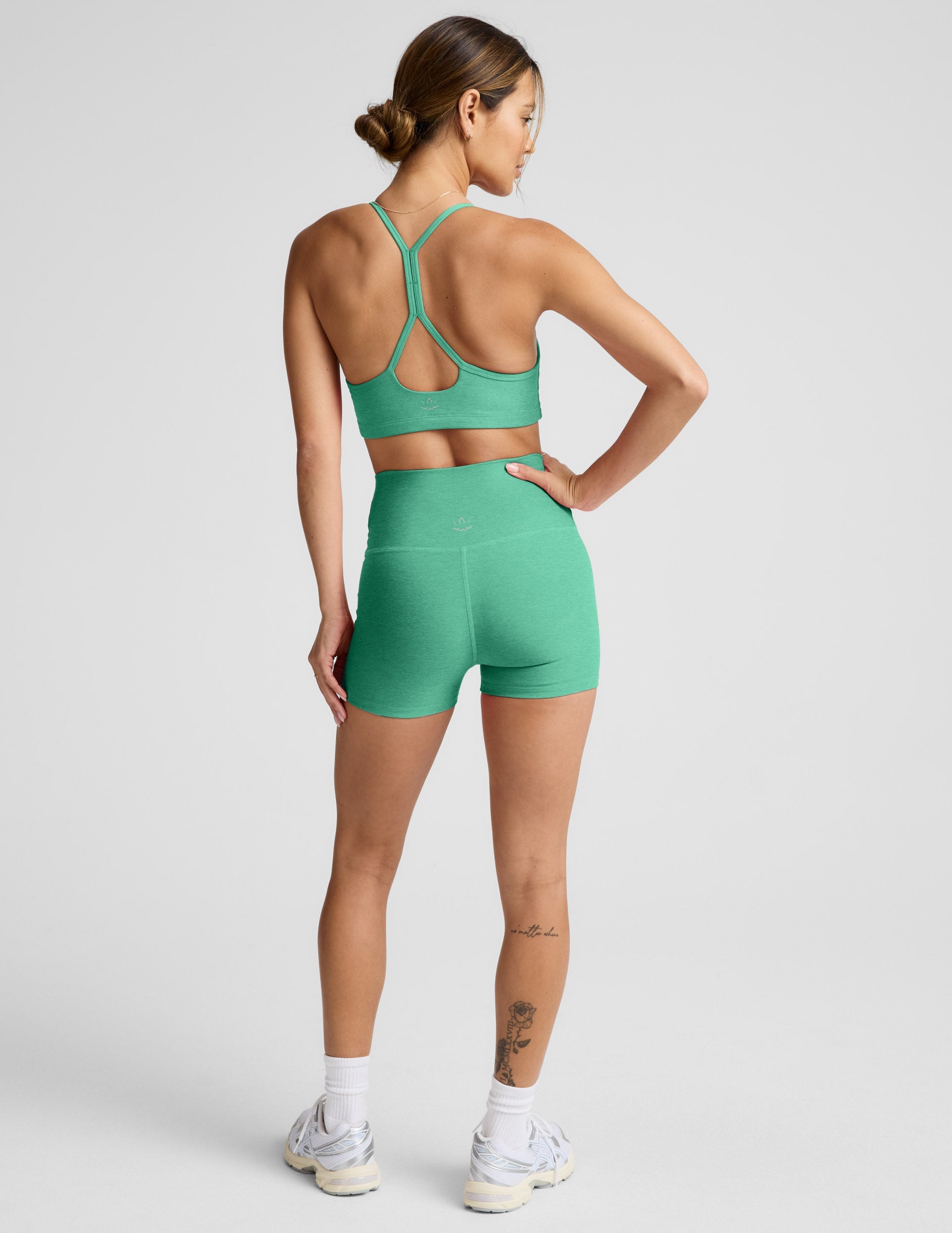 Back view of a woman wearing green Spacedye Keep Pace 3" Shorts with a high waistband and matching sports bra.