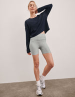 Woman in a relaxed pose wearing grey marled Spacedye Keep Pace 5" Short, a high-waisted fit, navy top, and white sneakers.