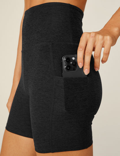 Spacedye Keep Pace Pocket Short in black marled fabric with a hand placing a phone into the high-waist side pocket.