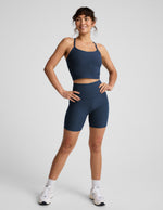Woman wearing a navy blue athletic outfit on a light gray background.
