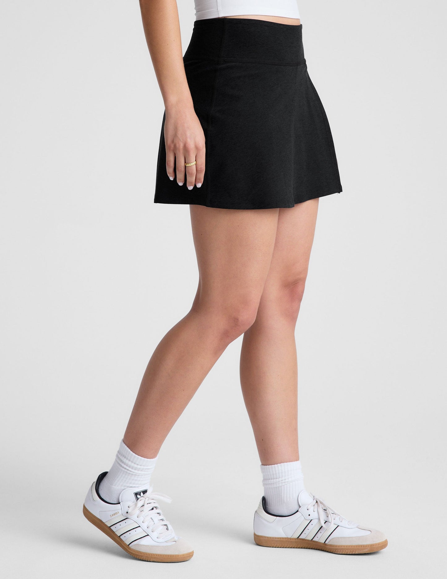 Side view of the black Spacedye Points Crossover Skirt, a high-waisted A-line mini skort with a side overlap slit.