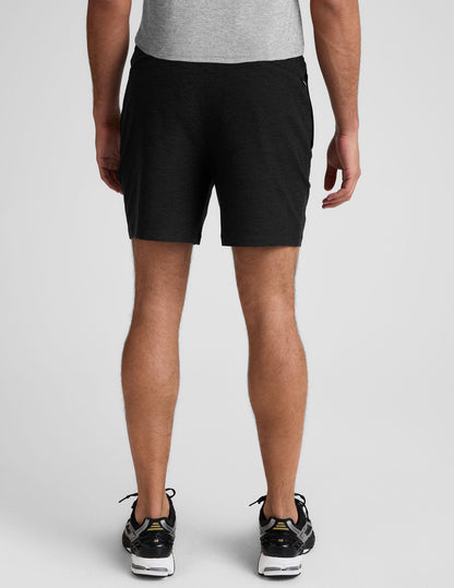 Rear view of a man wearing Spacedye Unlimited Men's Shorts in charcoal black with an elastic waistband and mid-thigh length.