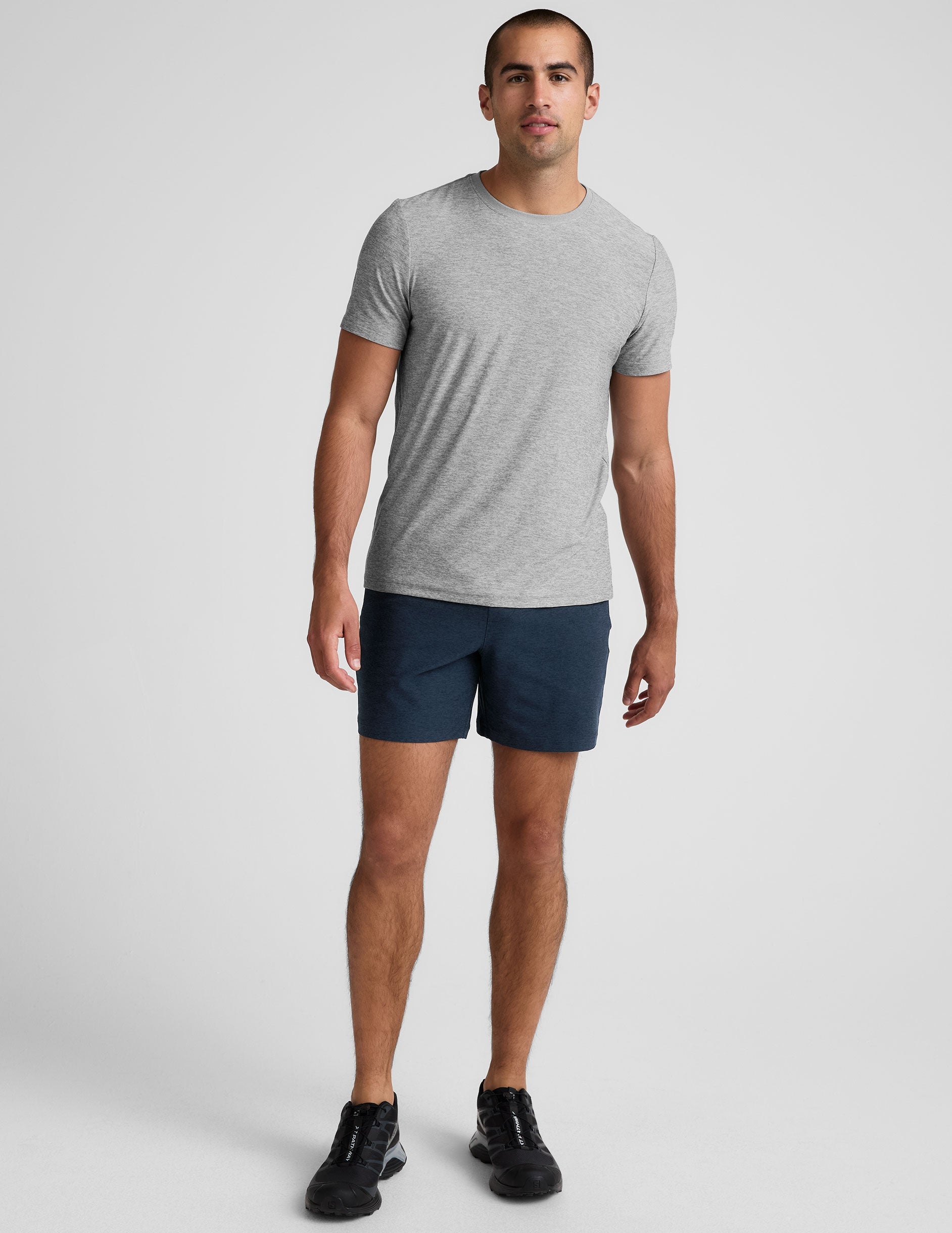 Man wears navy Spacedye Unlimited Men's Shorts with a 7" inseam, paired with a grey t-shirt and black sneakers.