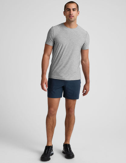 Man wears navy Spacedye Unlimited Men's Shorts with a 7" inseam, paired with a grey t-shirt and black sneakers.