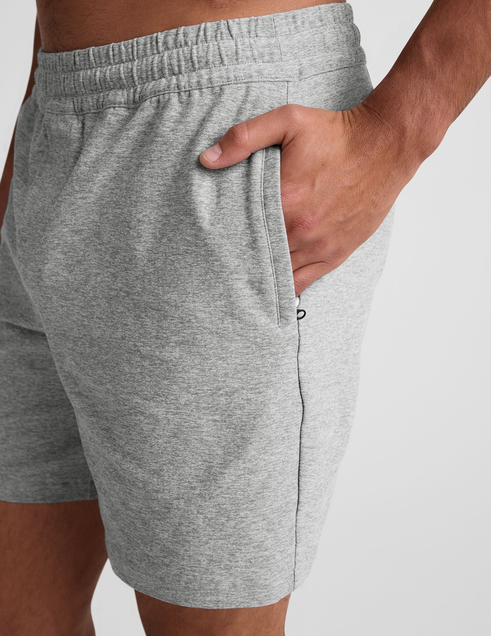 Close-up of Spacedye Unlimited Men's Short in heather gray with a hand in the side zippered pocket and elastic waistband.