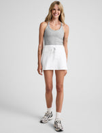 Woman wearing the white Spacedye Go Pocket Skirt, a high-waisted mini skirt with a front drawcord and A-line fit.