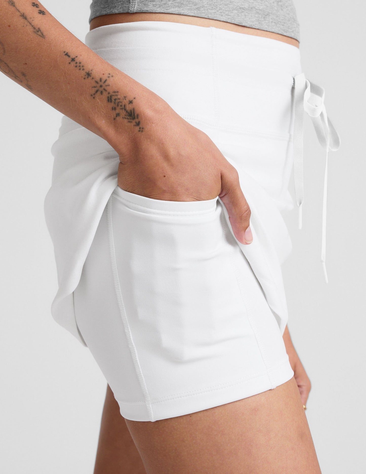 Side view of white Spacedye Go Pocket Skirt showing high drawstring waist and built-in liner shorts with a side pocket.