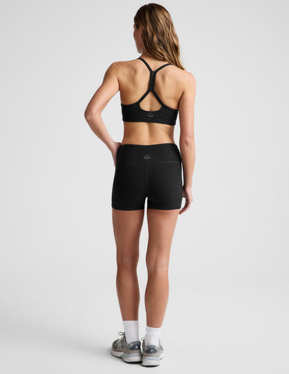 Rear view of a model in black Spacedye Keep Pace 3" Mid-Rise Shorts showing the snug fit, mid-rise waist, and short length.