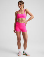 Woman wearing Fuchsia Spacedye Keep Pace 3" Mid-Rise Short paired with a matching sports bra and pink sneakers.