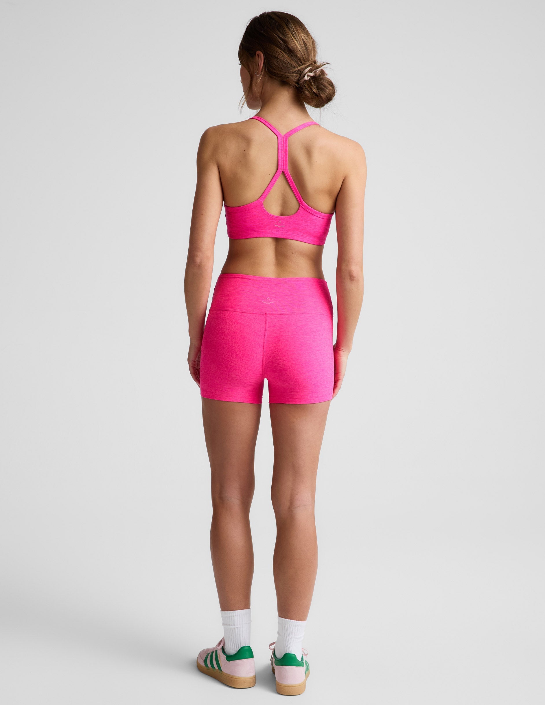 Rear view of woman wearing Fuchsia Spacedye Keep Pace 3" Mid-Rise Short paired with a matching sports bra and white socks.