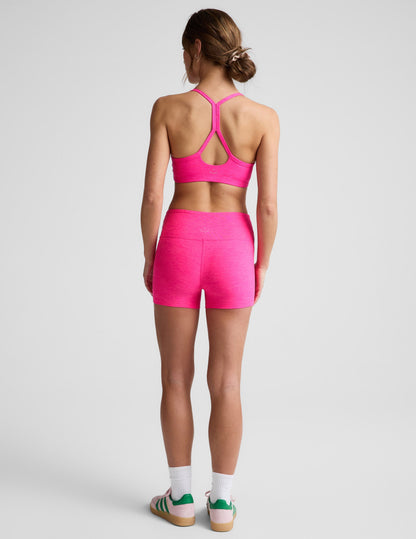 Rear view of woman wearing Fuchsia Spacedye Keep Pace 3" Mid-Rise Short paired with a matching sports bra and white socks.