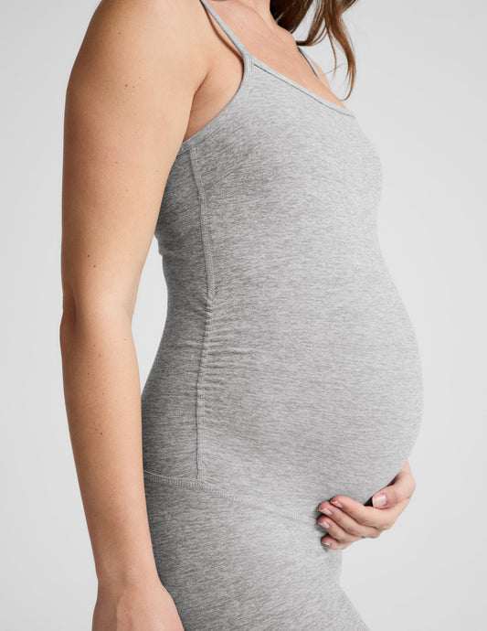 Woman wearing a gray maternity jumpsuit on a white background.