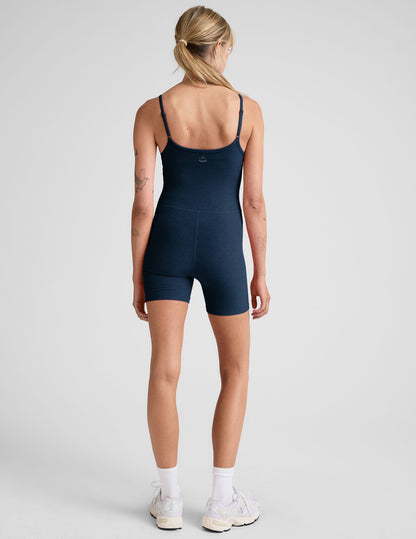 model is wearing a navy blue biker jumpsuit against a plain background.