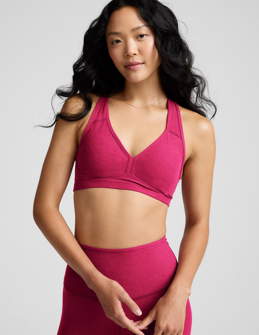 Woman wearing a red sports bra and leggings against a plain background.