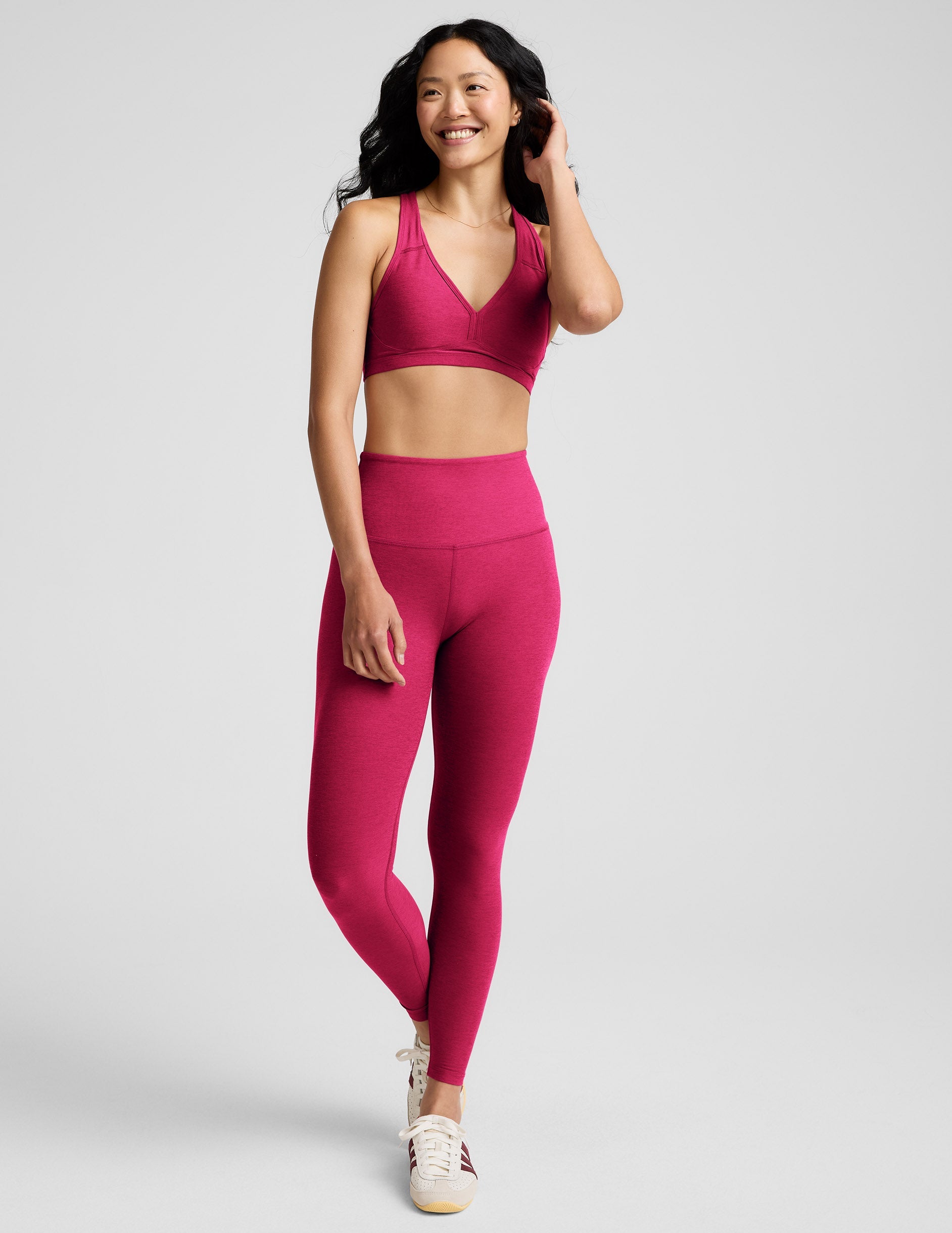 Woman wearing a red sports bra and leggings against a plain background.