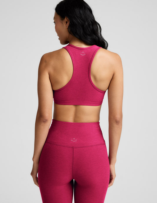 Woman wearing a red sports bra and leggings against a plain background.