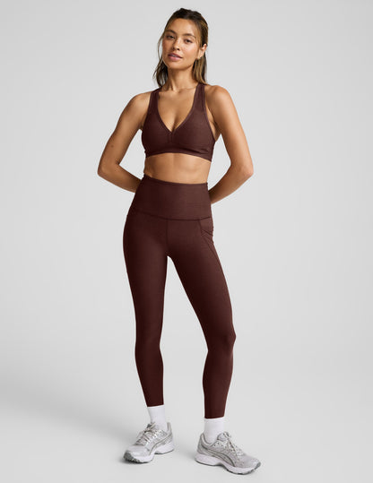 Woman wearing a brown sports bra and leggings against a light gray background.