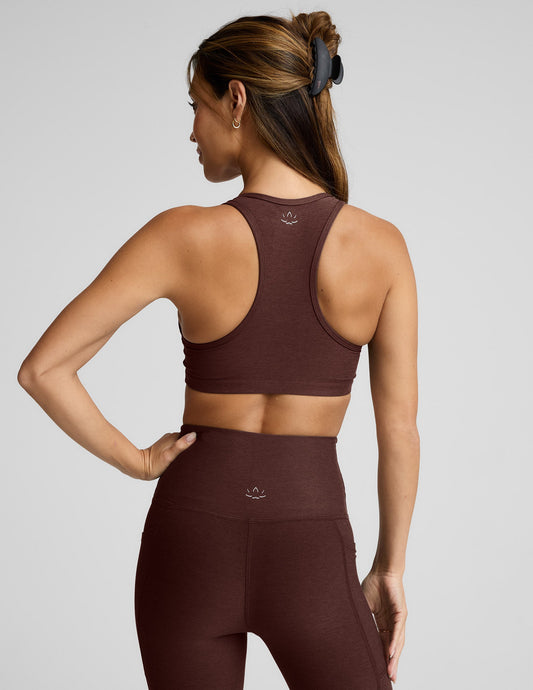 Woman wearing a brown sports bra and leggings against a light gray background.