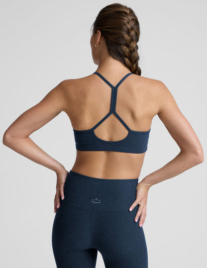 person wearing a blue slim racerback bra with leggings against a plain background.