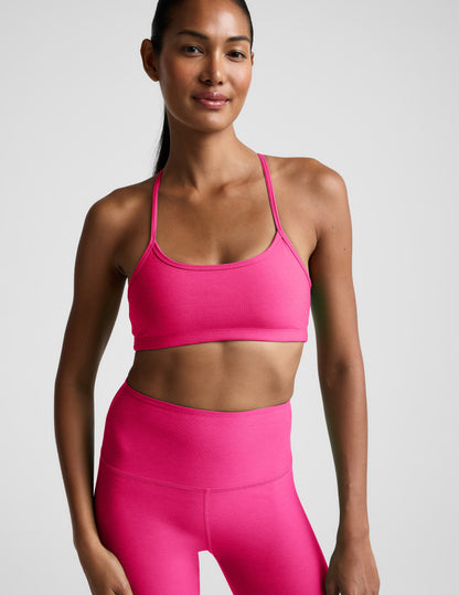 Woman wearing a bright pink sports bra and leggings on a light gray background.