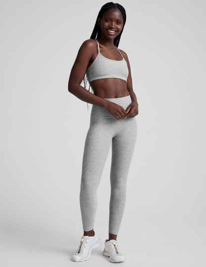 model is wearing a gray racerback bra with slim spaghetti straps and leggings against a plain background.