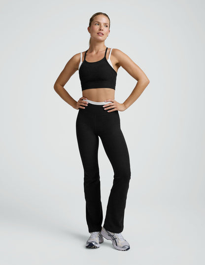 Woman wearing a black and white layered racerback sports bra and leggings on a plain background.