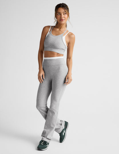 Woman wearing a gray sports bra and pants on a light gray background.