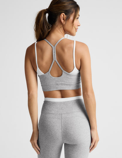 Woman wearing a gray sports bra and pants on a light gray background.