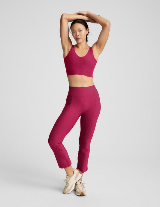 Woman wearing a red long line bra and leggings on a light gray background.