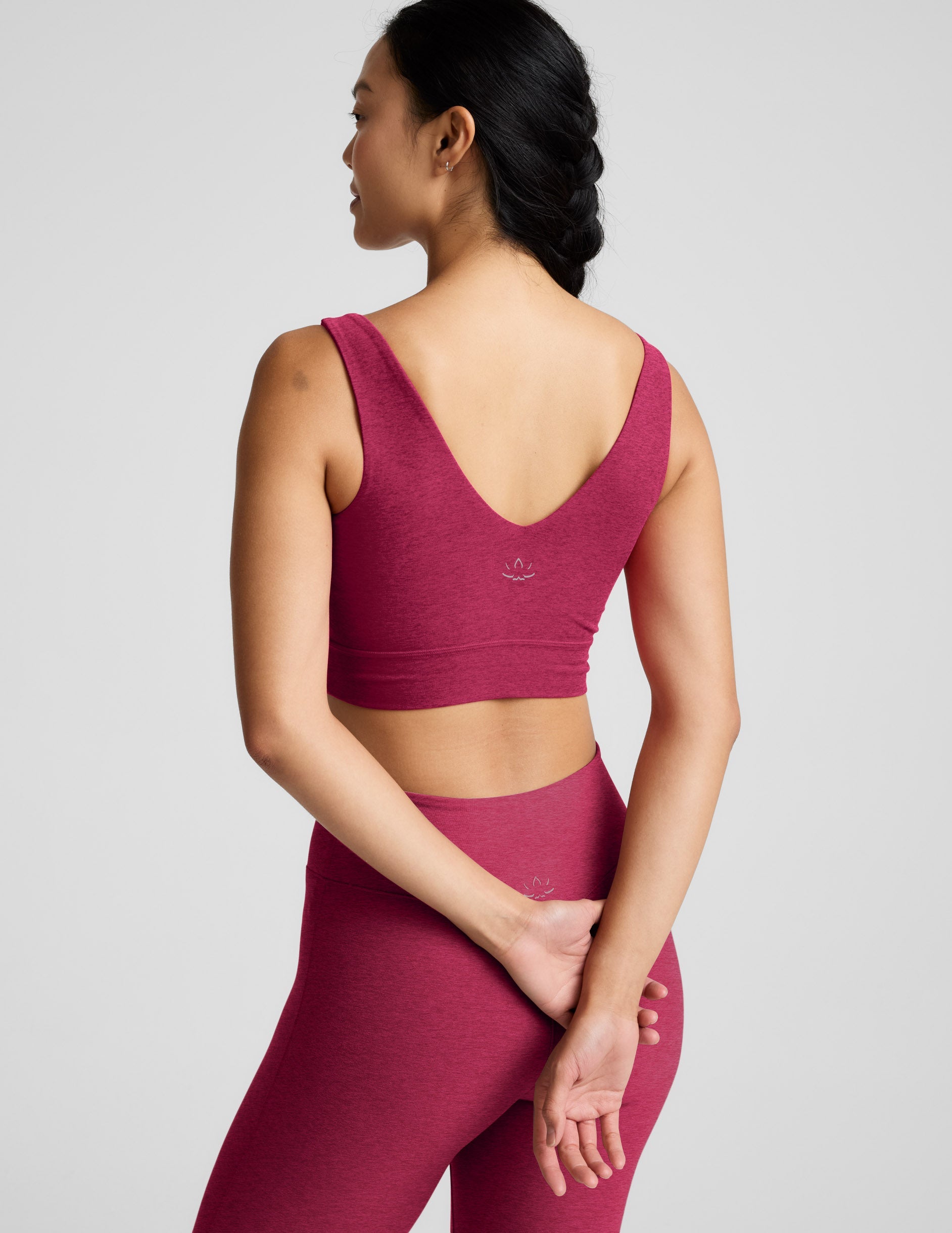 Woman wearing a red long line bra and leggings on a light gray background.