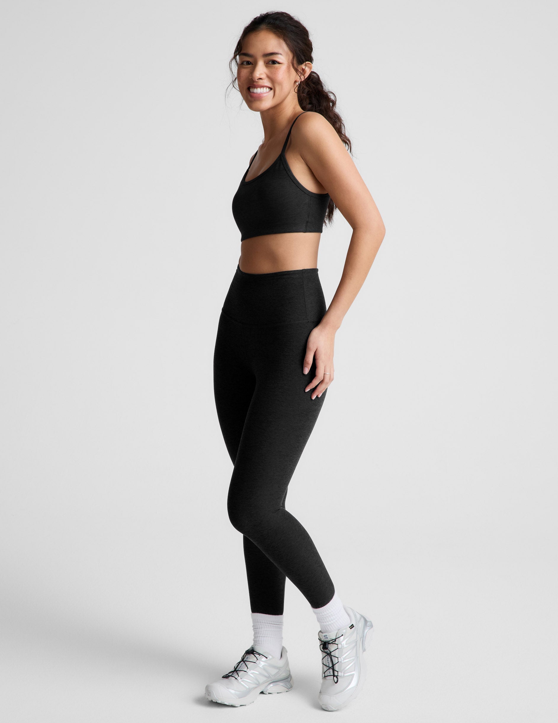 Woman wearing a black bra and leggings against a plain background.