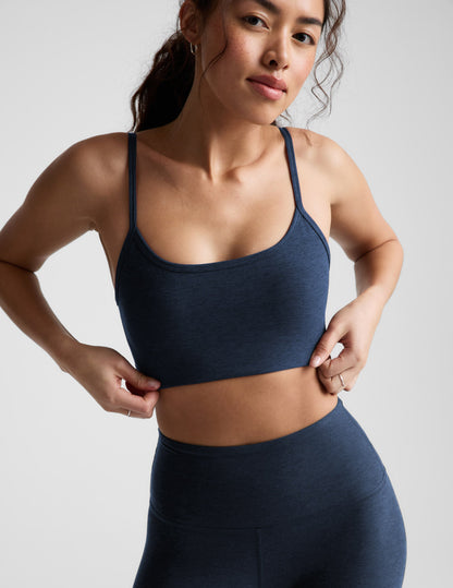 Woman wearing a blue bra and leggings against a plain background.
