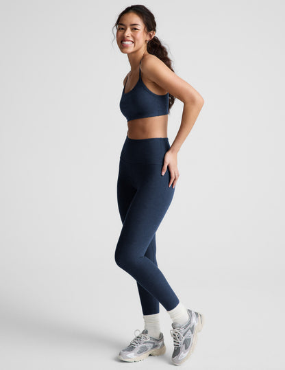 Woman wearing a blue bra and leggings against a plain background.