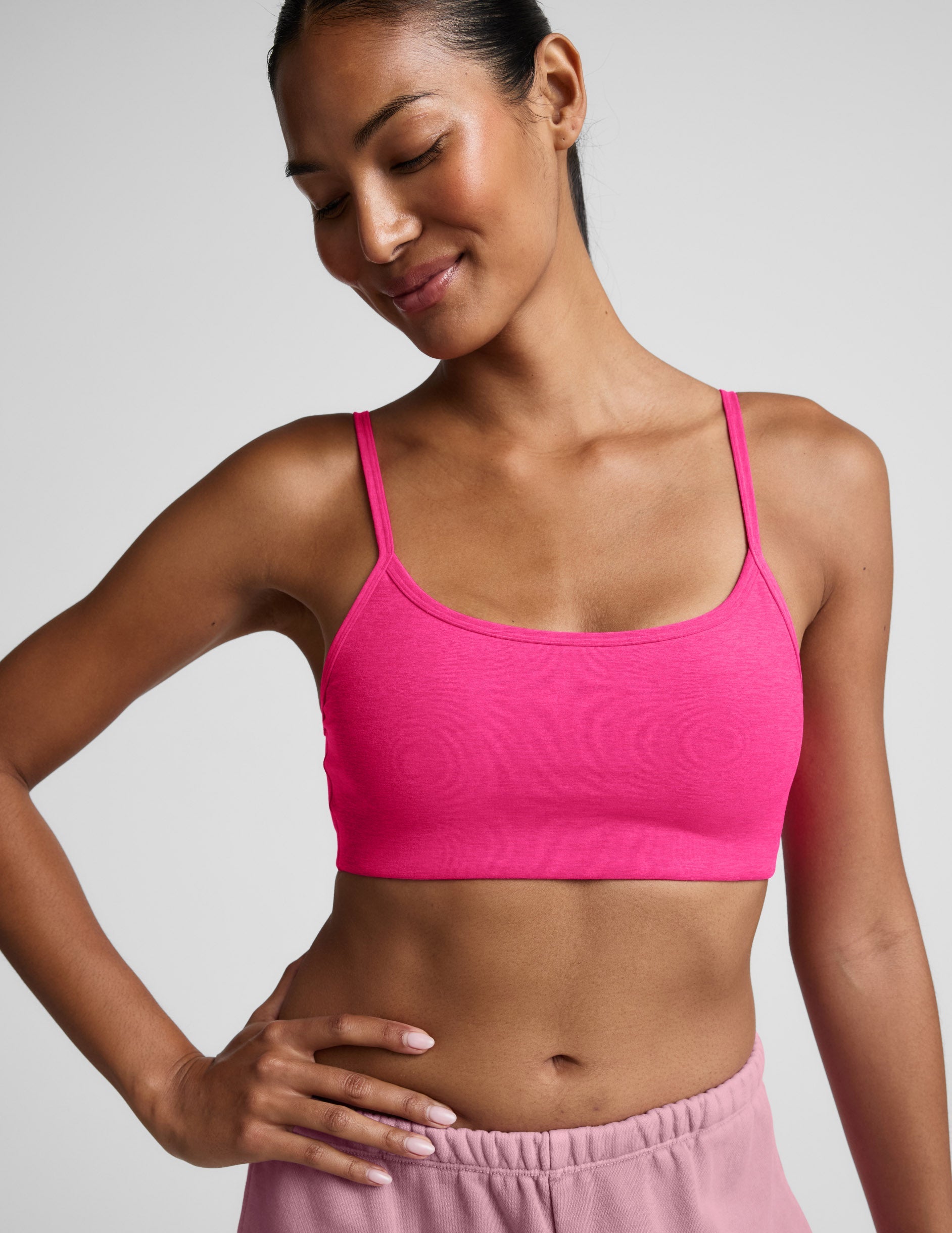 Woman wearing a pink sports bra and shorts on a plain background.
