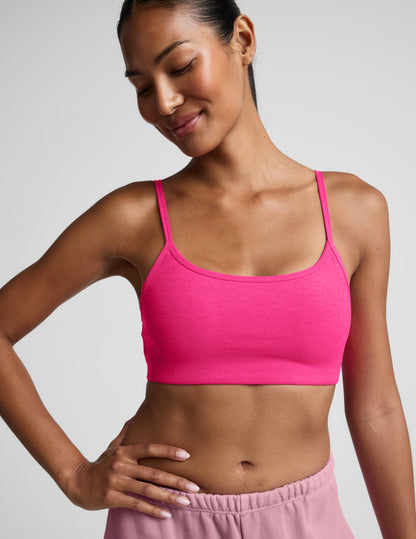 Woman wearing a pink sports bra and shorts on a plain background.