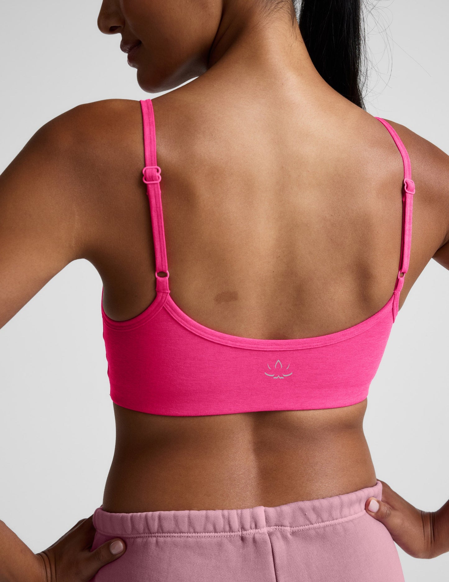 Woman wearing a pink sports bra and shorts on a plain background.