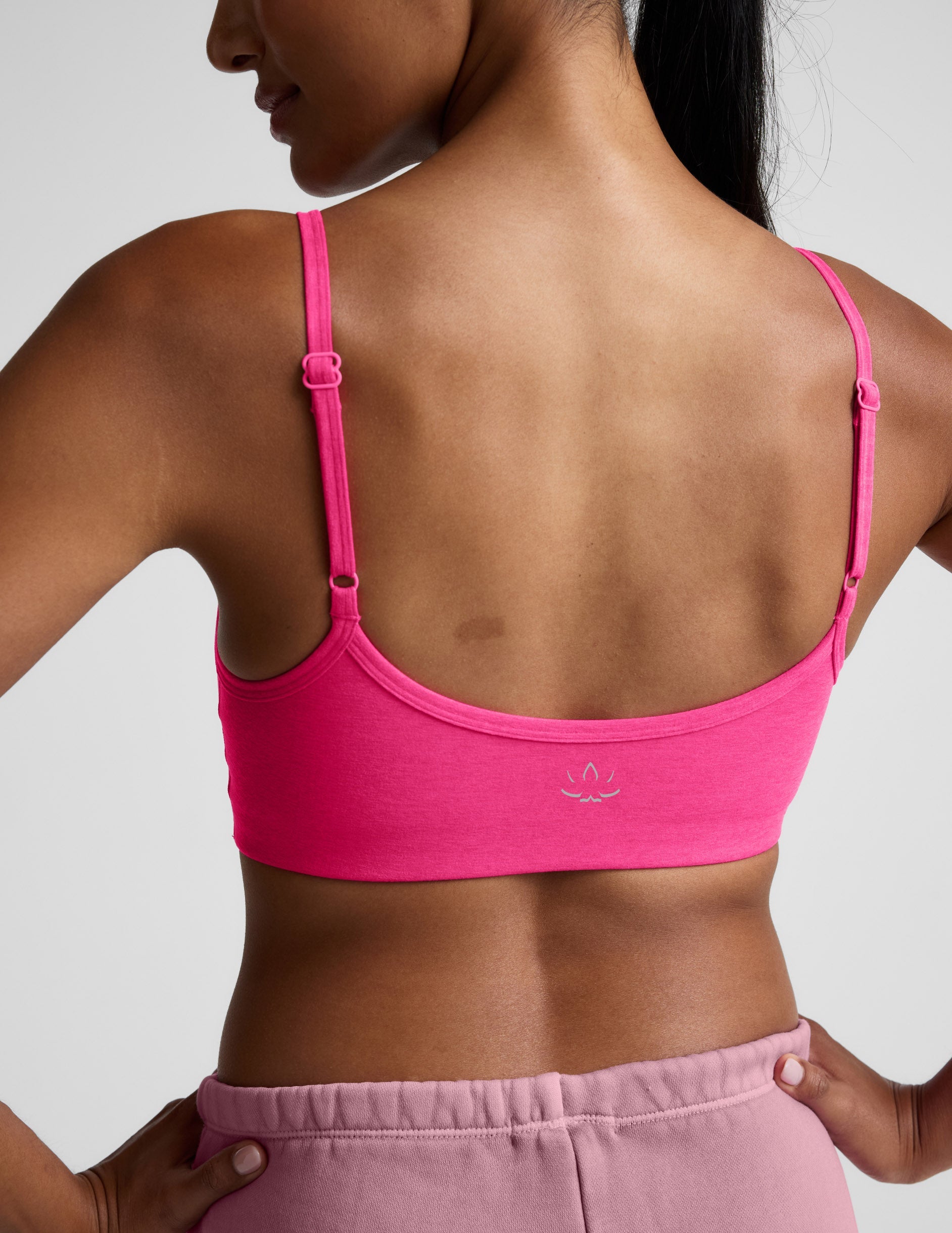 Woman wearing a pink sports bra and shorts on a plain background.