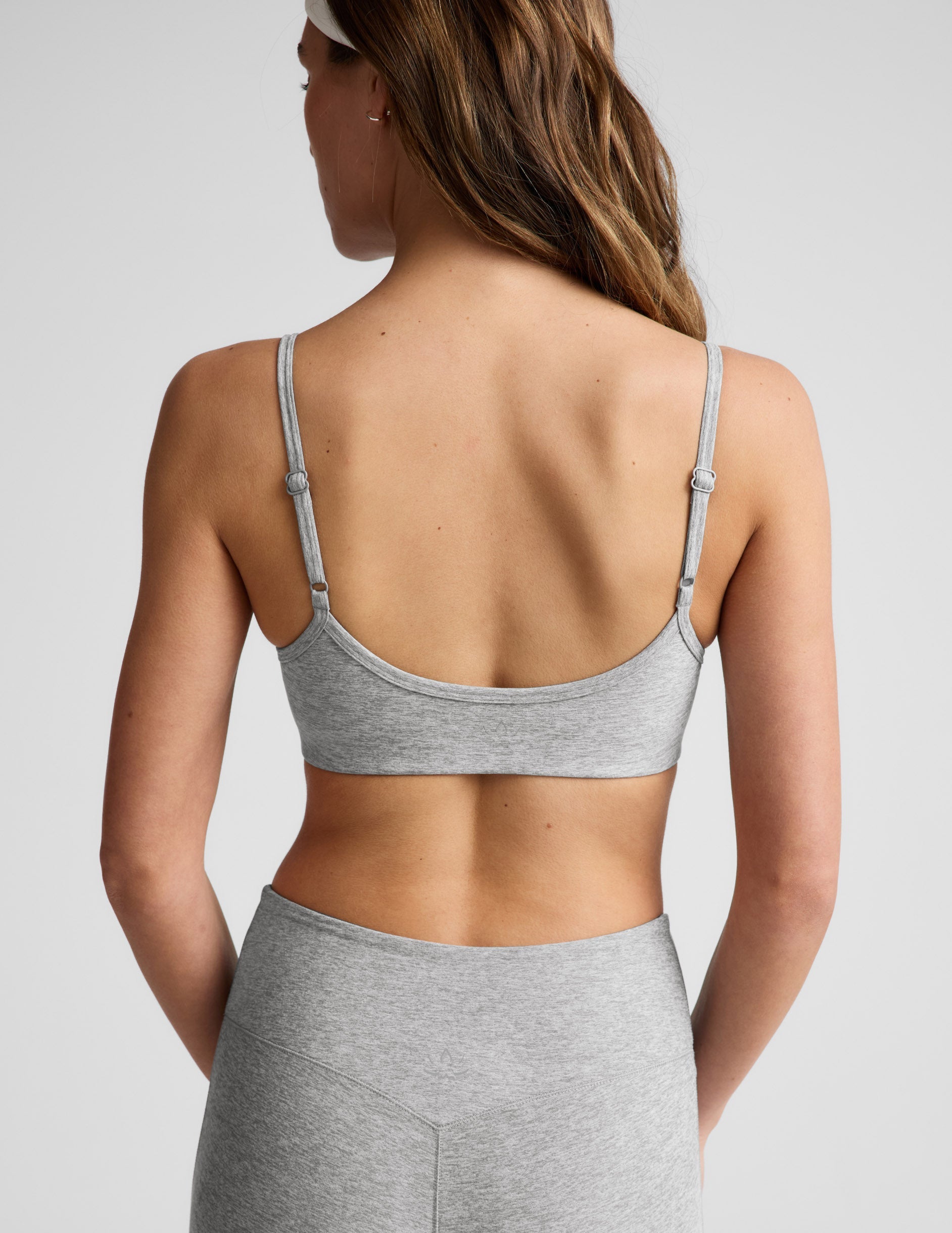Woman wearing gray bra and pedal pushers against a plain background.