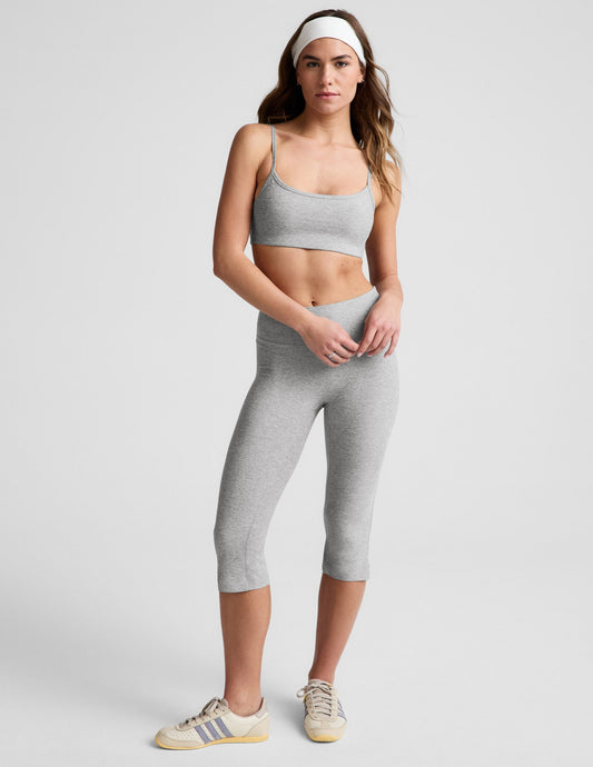 Woman wearing gray bra and pedal pushers against a plain background.