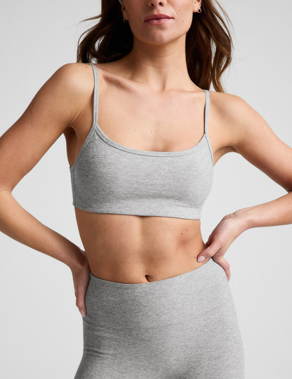 Woman wearing gray bra and pedal pushers against a plain background.