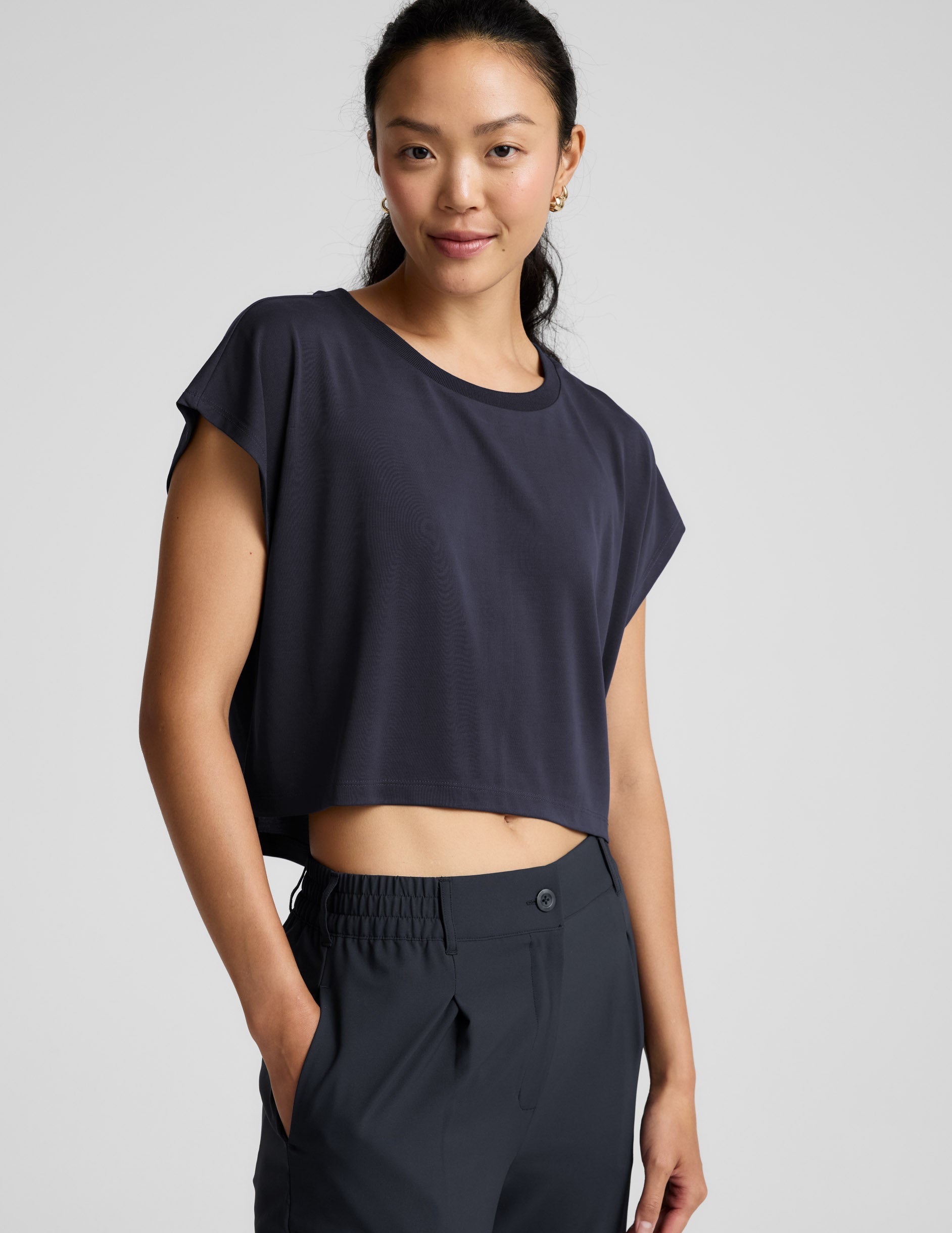 Woman wearing a blue shorts and trousers on a plain background.