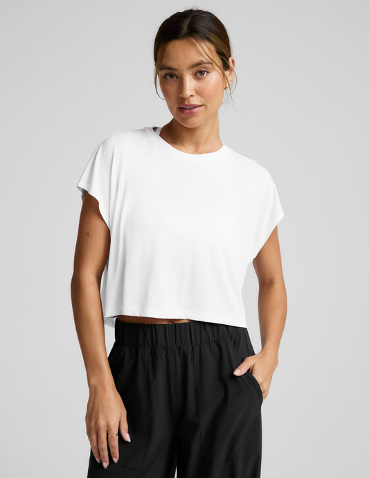 Woman wearing a white top and black pants on a gray background.