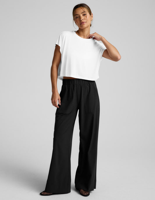 Woman wearing a white top and black pants on a gray background.