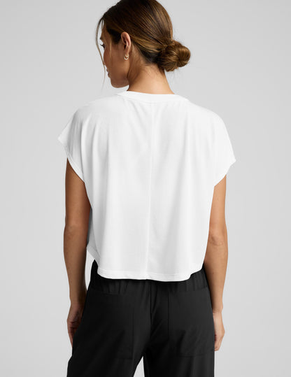 Woman wearing a white top and black pants on a gray background.