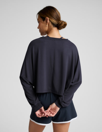 Woman wearing a blue long-sleeve top and blue shorts with white drawstrings on a gray background.