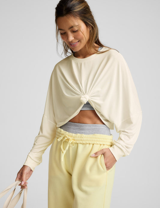 Woman wearing a light yellow long-sleeve top and pants on a plain background.