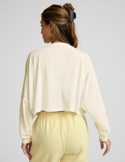 Woman wearing a light-colored outfit with a plain background.
