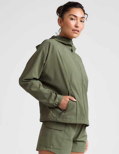 model is wearing an olive green zip-up jacket with side pockets and a hood on a white background.